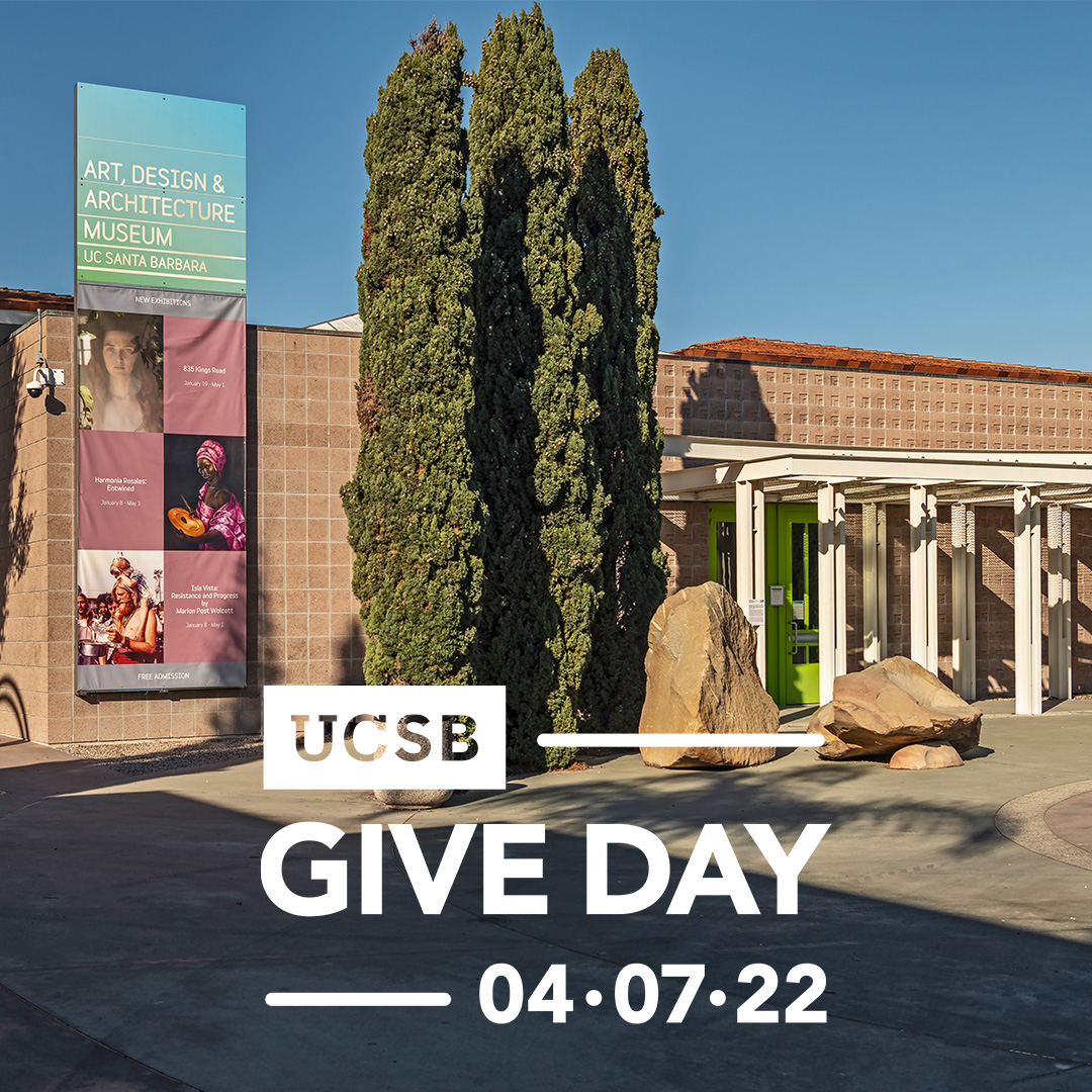 Front entrance of Art, Design & Architecture Museum, with trees and multi-color banner. In white, "UCSB Give Day 04-07-22" center bottom.