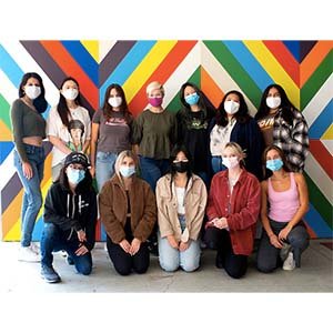 Student interns in front of geometric, colorful mural.